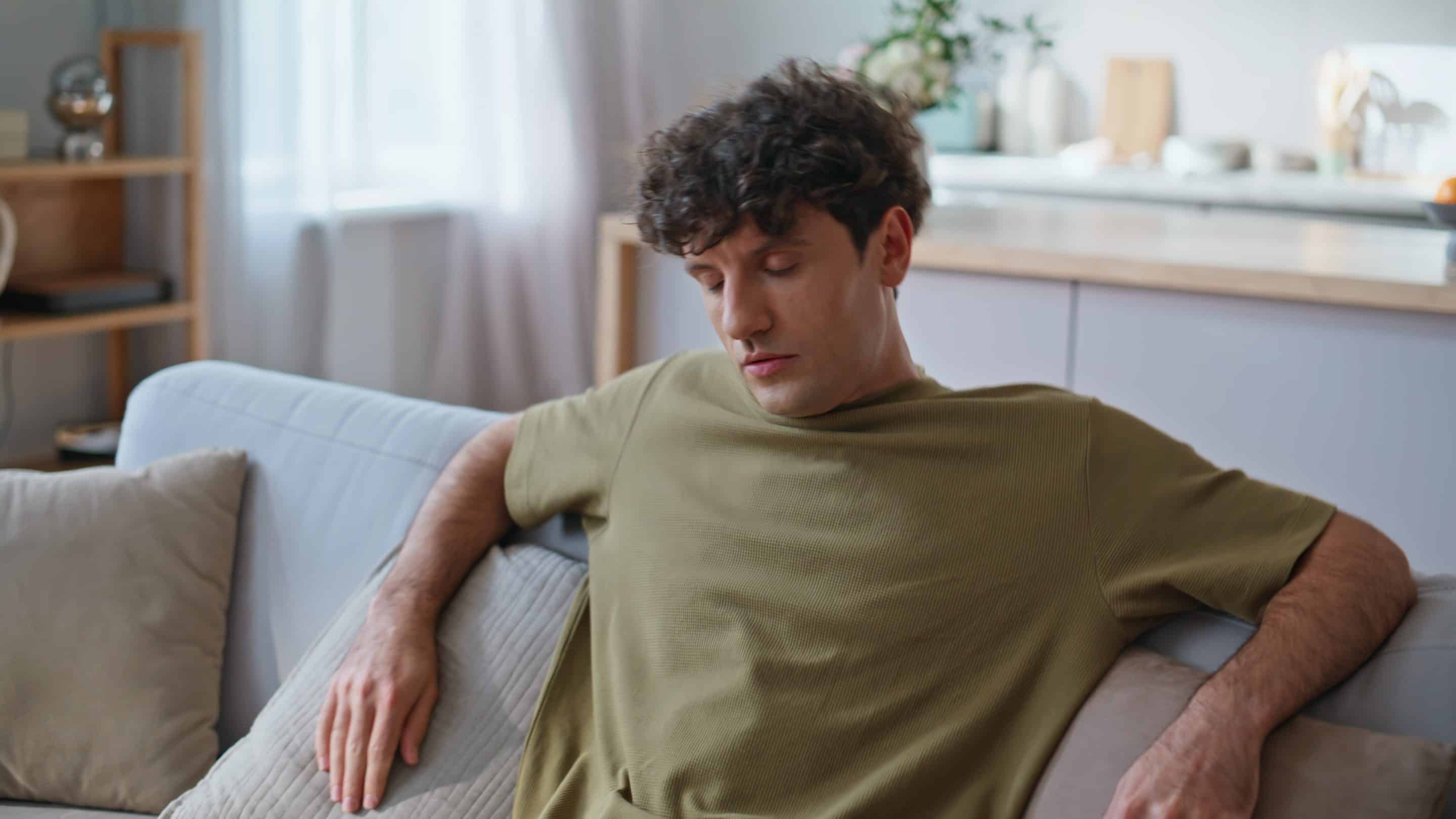 Closeup tired freelancer falling on couch taking work break at home. Guy resting